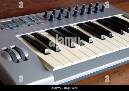 Clavier synthétiseur électronique avec roues de contrôle et boutons en argent corps en plastique sur fond de bois gros plan Vue de côté Banque D'Images