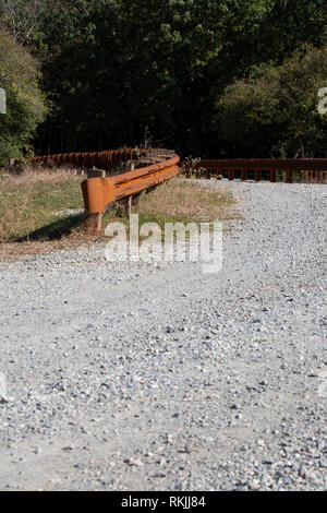 Pont de fer rouillé garde-corps sur une route de gravier Banque D'Images