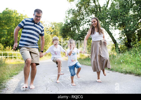 Une famille avec deux petits fils hopscotching pieds nus sur une route dans le parc sur une journée d'été. Banque D'Images