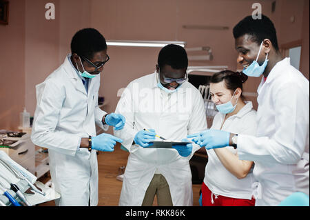 L'équipe médecins dentiste multiraciale. Trois médecins hommes afro-américains avec un portrait de femmes. Ils discuter et rire. Banque D'Images