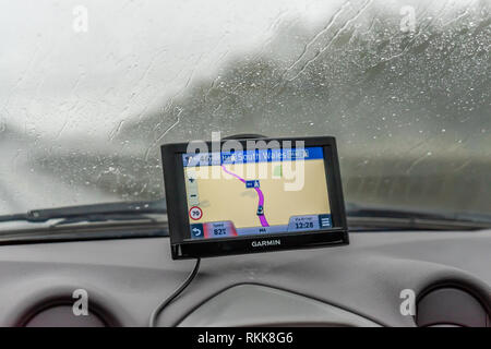 Un Garmin GPS ou système de navigation par satellite, monté sur un écran du vent voiture en temps de pluie, UK Banque D'Images