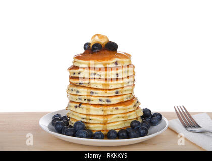 Fluffy pancakes aux myrtilles haut empilées, de bleuets frais, du beurre et du sirop, sur l'assiette de porcelaine sur une table en bois clair. Fourchette et serviette à côté, isoler Banque D'Images