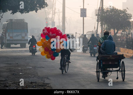 Man riding bicycle exerçant son gros bouquet de ballons à Amritsar, Inde Banque D'Images