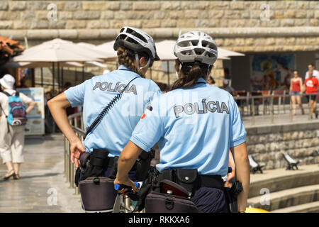 Deux femmes policiers de Cascais, patrouillent promenade de bord sur des bicyclettes. Les gens sont des rayons sur la ville plage publique sur la côte atlantique. Banque D'Images