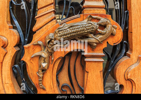 Art nouveau ouvragée porte de bois détail avec motif organique et une figurine en bronze d'un lézard de manger un épi de maïs pour une poignée de porte à Paris, France Banque D'Images