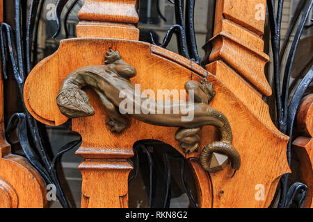 Art nouveau ouvragée porte de bois détail avec motif organique et une figurine en bronze d'un lézard pour une poignée de porte à Paris, France Banque D'Images