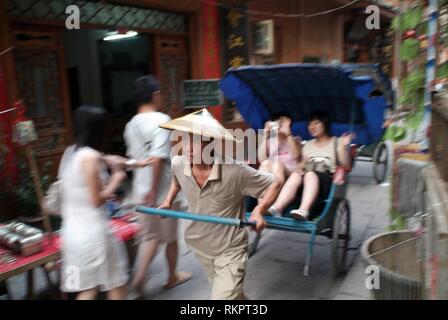 Un chauffeur de pousse-pousse attire les touristes dans les ruelles de Fenghaung Banque D'Images