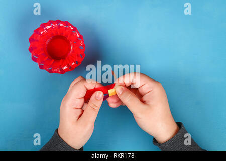 Oeuf de Pâques Diy panier fait de plastique rouge décoré de fleurs artificielles fond bleu. Idée cadeau décoration, Printemps, Pâques. Étape par étape. Haut de page vi Banque D'Images