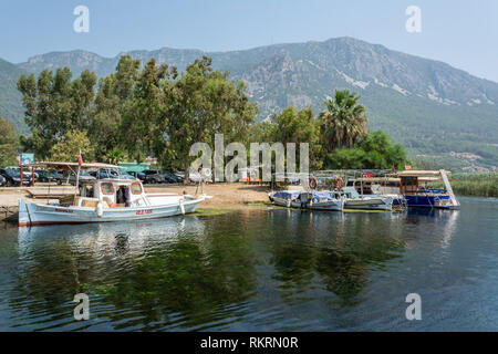 Akyaka, Mugla, Turquie - 30 juillet 2016. Flux Azmak dans Akyaka village de Mugla province de la Turquie, avec des bateaux et Sakar montagnes en arrière-plan. Banque D'Images