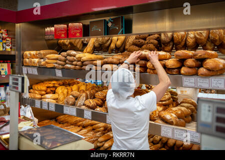 Un membre du personnel sortes de pain frais dans une pâtisserie, pâtisserie, dans la ville de Valence, Espagne. Banque D'Images