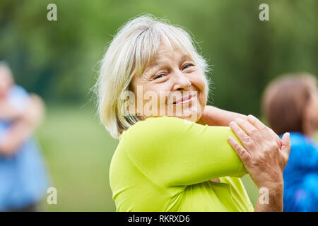 Senior woman doing stretching un exercice pour les bras supérieurs à la salle de gym class Banque D'Images