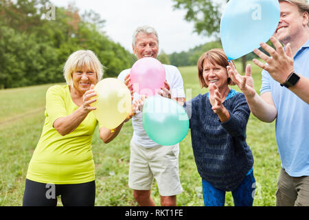 Les personnes âgées gaies jouant avec des ballons colorés lors d'une fête d'été Banque D'Images