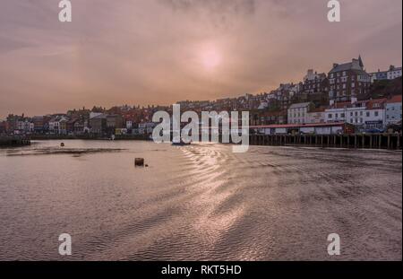 Whitby Harbour à l'intérieur. Les bâtiments de la ville vers le haut de la pile à côté de la voie d'eau comme les petits bateaux laisse un service qui attrape le soleil. Un clou Banque D'Images