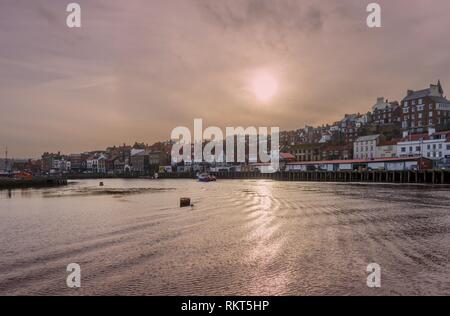 Whitby Harbour à l'intérieur. Les bâtiments de la ville vers le haut de la pile à côté de la voie d'eau comme les petits bateaux laisse un service qui attrape le soleil. Un clou Banque D'Images