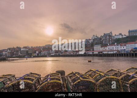 Whitby Harbour à l'intérieur. Les bâtiments de la ville vers le haut de la pile à côté de la voie navigable et il y a des casiers à homard à l'avant-plan. Un ciel nuageux je Banque D'Images