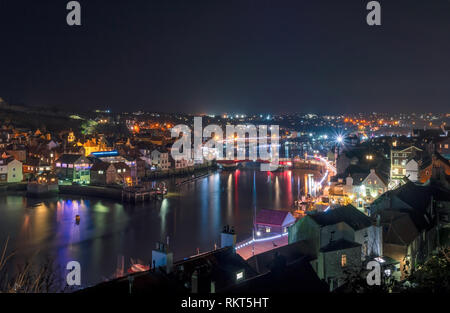 Une scène de la ville et le port de Whitby allumé jusqu'à la nuit. Les chambres lumineuses, lumières colorées se reflètent dans l'eau et un ciel sombre est ci-dessus. Banque D'Images