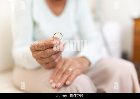 Navré femme âgée maintenant il mari anneau de mariage Banque D'Images