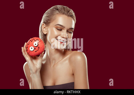 Cheerful woman holding donut rose avec de grands yeux Banque D'Images