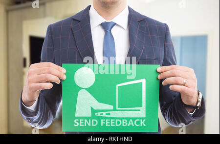 Man holding green paper avec envoyer des commentaires texte et dessin de personne qui écrit sur l'ordinateur portable Banque D'Images