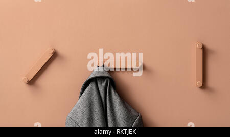 Les cintres en métal fantaisie avec de la veste grise sur mur coloré dans studio Banque D'Images