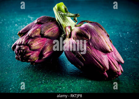 Fleur d'Artichaut frais. Artichauts bio brut foncé sur fond de béton, copy space Banque D'Images