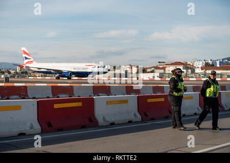 Un Airbus A320 de British Airways traverse la piste, tandis que le trafic et les piétons, d'attente dans le célèbre passage de l'aéroport à Gibraltar Banque D'Images