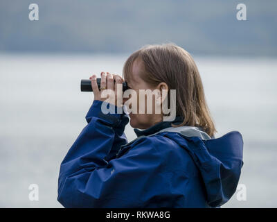 Femme à l'aide de jumelles pour observer la faune marine en mer Loch Slapin, Isle of Skye, Scotland, UK Banque D'Images