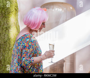 Une dame avec une perruque rose et un verre de prosecco à la latitude Festival 2018. Banque D'Images