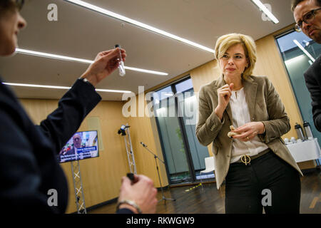 Berlin, Allemagne. 12 Février, 2019. Nutrition fédéral Ministre Julia Klöckner (CDU) tente un morceau de pain sur un "goût" qui a été créé à l'occasion de la première réunion de la commission d'accompagnement de la stratégie du gouvernement fédéral pour moins de sucre, de gras et de sel. Un représentant de l'organisateur, l'Institut Max Rubner, détient les conteneurs qui montrent la quantité de sel contenue dans différents types de pain. Crédit : Carsten Koall/dpa/Alamy Live News Banque D'Images