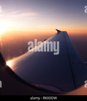 POV passager Vue à travers la fenêtre de l'avion, le lever du soleil au-dessus des nuages Aerial Banque D'Images