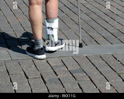 Les pieds avec l'attelle, orthèse de jambe. Personne après une marche de canne ou cassé les jambes entorse. Pour l'orthèse orthopédique immobilisant pied Banque D'Images