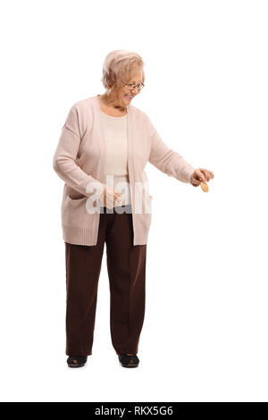 Full Length portrait of a senior woman smiling, tenant un biscuit et regardant vers le bas isolé sur fond blanc Banque D'Images