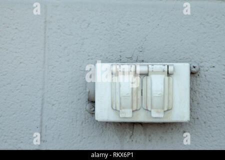 Vieille prise électrique nord-américaine rustique sur un mur extérieur en brique gris Banque D'Images