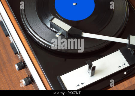 Old vintage vinyl record player dans la caisse en bois brun à l'enregistrement LP avec étiquette bleue. Vue de dessus gros plan photo horizontale Banque D'Images