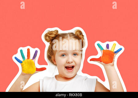 Petite fille joyeuse enfant montre des mains peints avec de la peinture. Fond orange, portrait Banque D'Images