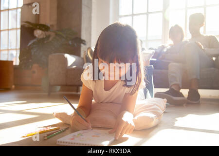 Cute kid girl dessin avec des crayons lying on floor Banque D'Images
