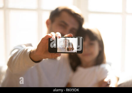 Père holding phone en tenant avec selfies kid fille sur smartphone Banque D'Images