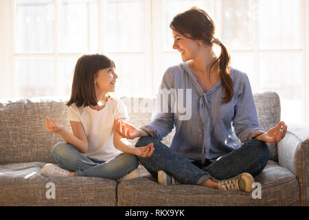 L'enseignement du yoga maman l'esprit heureux enfant fille sitting on couch Banque D'Images