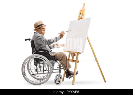 Profil de toute la longueur d'un homme mature dans un fauteuil roulant de peindre sur une toile isolé sur fond blanc Banque D'Images