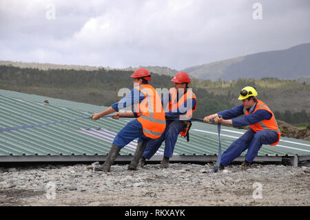 Builders tirer sur la ligne pour positionner le toit pour le levage sur un nouveaux produits laitiers, Westland, Nouvelle-Zélande Banque D'Images