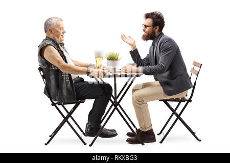 Profil de toute la longueur d'un homme mûr dans une veste en cuir de boire une bière à une table et de parler avec un jeune homme barbu isolé sur fond blanc Banque D'Images