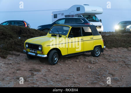 Voiture Renault 4 jaune garée convertible oldtimer à Stony parking par la mer au coucher du soleil. CAPE ST. VINCENT, LE PORTUGAL - 5 septembre 2018. Banque D'Images