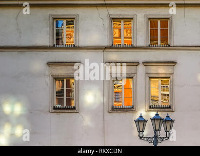 Lumière de rue et six vieilles fenêtres sur le mur avec des reflets de la vieille ville de Cracovie au lever du soleil Banque D'Images