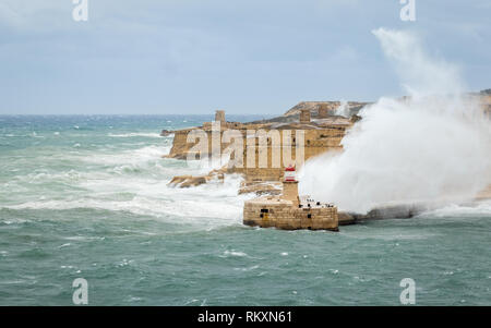 Brise-lames Est Ricasoli et phare de résister à la mer de matières premières et de hautes vagues. Fort Ricasoli, Kalkara, Malte, l'Europe. Banque D'Images