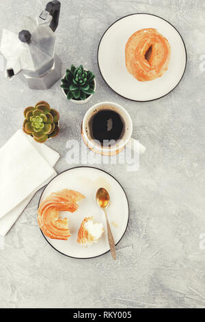 Le petit-déjeuner avec anneaux - chou à la crème, pâte à choux et tasse de café noir sur fond clair Banque D'Images