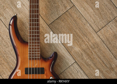 Puissance de l'instrument de musique. Vue de dessus de la guitare électrique brun couché sur le plancher en bois. Des appareils de musique. Instruments de musique. Concept Musique Banque D'Images