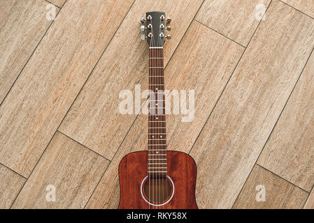 L'instrument le plus élégant. Vue de dessus de la guitare acoustique brun couché sur le plancher en bois. Instruments de musique. Des équipements de musique Banque D'Images