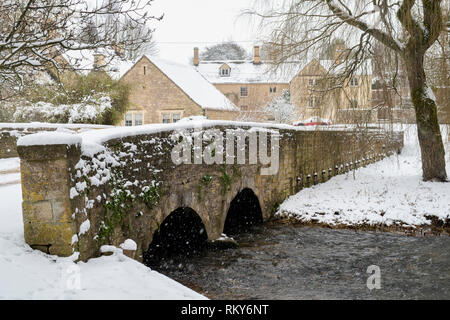 Rivière colne et pont de pierre dans le village de Cotswold Ablington dans la neige de l'hiver. Ablington, Cotswolds, Gloucestershire, Angleterre Banque D'Images