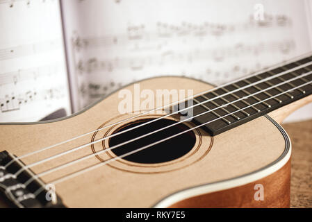 Ukulele chords. Photo en gros plan d'ukulele guitare et les notes de musique de fond de bois contre. Banque D'Images