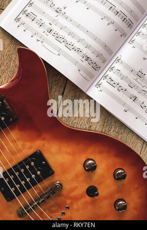 Accords de guitare électrique. Photo en gros plan d'une guitare électrique corps avec boutons de commande de volume et tonalité avec notes de musique de fond de bois contre. Instruments de musique. L'éducation musicale. Banque D'Images